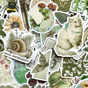 May include: A collection of decorative stickers with a botanical and animal theme. The stickers feature a variety of designs, including a snail with the text "SNAIL ENTHUSIAST", a white cat, a bee, a sunflower, and a butterfly. The color palette includes green, yellow, and brown.