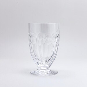 Op de afbeelding: Een helder drinkglas met steel en een gestructureerd patroon. Het glas heeft een brede, afgeronde body die taps toeloopt naar een kleinere voet. Het glas is gemaakt van helder glas en staat tegen een witte achtergrond.
