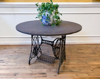Antique Outdoor Patio Dining Table with Cast Iron Singer Sewing Machine Base and Round Gray Slate Top.