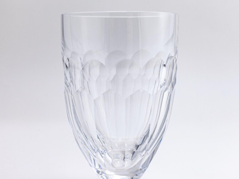 Op de afbeelding: Een helder glas met steel en een gestructureerd, geometrisch patroon. Het glas heeft een brede kom en een smalle voet. Het patroon bestaat uit kleine, afgeronde vormen die een honingraateffect cre&euml;ren. Het glas is waarschijnlijk van kristal.