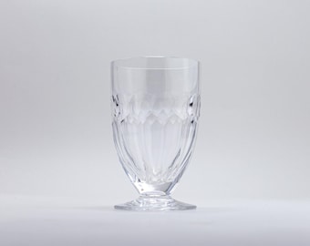 May include: A clear, stemmed drinking glass with a textured, diamond-like pattern on the sides. The glass has a wide, stable base and a smooth rim. The design is symmetrical and elegant, suitable for serving beverages.