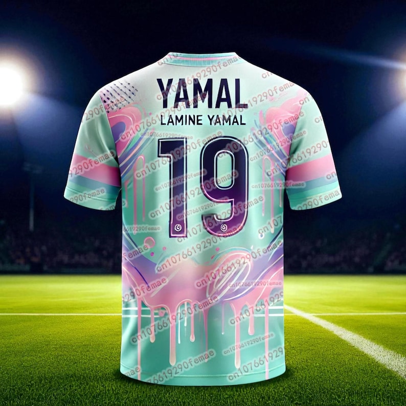 May include: A mint green soccer jersey with the name "YAMAL" and the number "19" on the back. The jersey has a colorful design with pink and purple accents. The jersey is displayed on a green field.