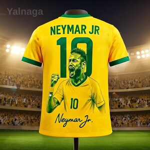 May include: Yellow Neymar Jr. soccer jersey with green trim. The number 10 is printed in green, along with Neymar Jr.'s name and a portrait of him celebrating. The jersey is displayed on a stand.