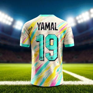 May include: A cream-colored soccer jersey with the name "YAMAL" and the number "19" on the back. The jersey has a colorful design with teal, yellow, and pink diagonal stripes. The sleeves and collar are teal.