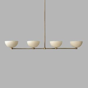 Op de afbeelding: Een moderne, minimalistische kroonluchter met vier crèmekleurige, komvormige kappen. De kappen zijn opgehangen aan een horizontale messing staaf en een verticale messing staaf. Het ontwerp is eenvoudig en elegant, geschikt voor diverse interieurstijlen.