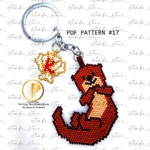 May include: A handmade keychain featuring a beaded otter charm in shades of brown and tan. The keychain also includes a gold and red beaded charm and a silver keyring. The text "PDF PATTERN #17" is visible.