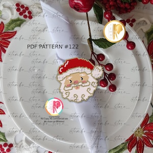 Puede incluir: Una cara de Papá Noel con cuentas, con un gorro rojo y barba blanca, se muestra en un plato blanco con una servilleta doblada. La imagen incluye el texto "PDF PATTERN #122". La cara de Papá Noel es una decoración festiva.
