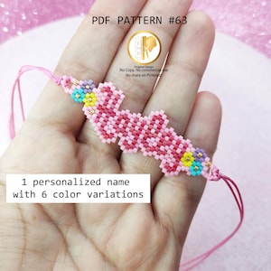 Puede incluir: Una pulsera de cuentas rosas que deletrea un nombre, con acentos de cuentas amarillas, azules y moradas. La pulsera está sujeta a un hilo rosa. La imagen también incluye el texto "PDF PATTERN #63" y "1 nombre personalizado con 6 variaciones de color."