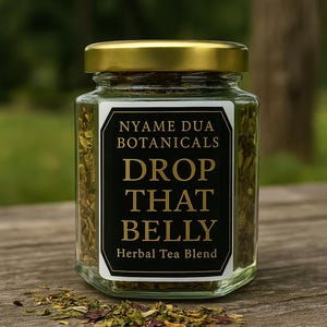 May include: A glass jar with a gold lid, containing dried green herbs. The label displays "NYAME DUA BOTANICALS DROP THAT BELLY Herbal Tea Blend" in gold text on a black and white label. The jar is placed on a wooden surface.
