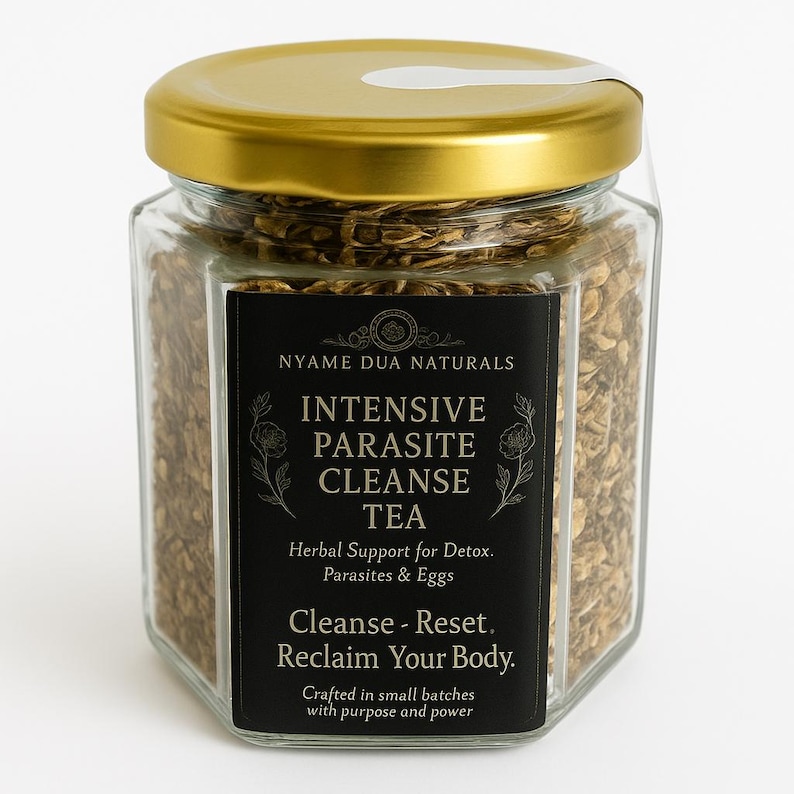 May include: A hexagonal glass jar filled with tea leaves, sealed with a gold lid. A black label displays the text "Intensive Parasite Cleanse Tea". The jar contains brown tea leaves, and the overall aesthetic is natural and health-focused.