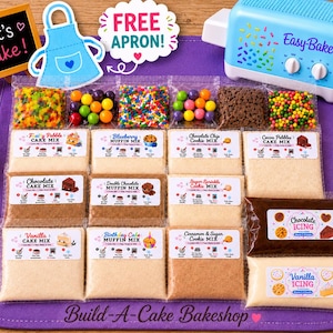 May include: A light blue Easy-Bake oven, a chalkboard sign reading Let's Bake, and a collection of baking supplies including various cake and muffin mixes, chocolate and vanilla icing, colorful sprinkles, and candy, all on a purple mat.