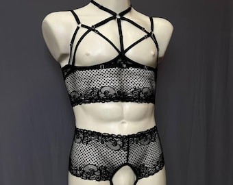 May include: A black lace lingerie set consisting of a cropped top and matching shorts. The top features a complex system of adjustable straps forming a harness design over the chest. Both pieces are made of a sheer, patterned lace fabric.