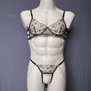 Peut inclure: Ensemble de lingerie en dentelle florale noire. L'ensemble comprend un soutien-gorge à bretelles réglables et un string assorti avec des chaînes. Le soutien-gorge et le string présentent un motif floral délicat. La lingerie est présentée sur un mannequin blanc.