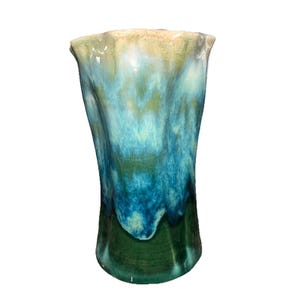 May include: A tall, ceramic vase with a unique, organic shape. The vase features a blend of colors, including shades of green, blue, and cream. The rim has a wavy edge. The glaze has a crackle effect, adding to its artistic appeal.