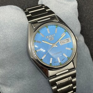 Pu&ograve; includere: Un orologio automatico Seiko 5 in acciaio inossidabile con quadrante azzurro. Il quadrante mostra il giorno e la data, con dettagli verdi e argento. Il cinturino dell'orologio &egrave; in acciaio inossidabile.