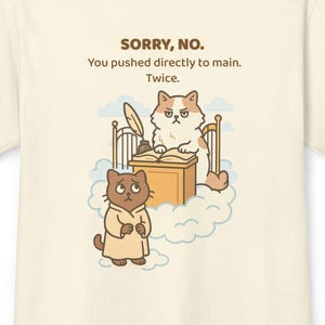 Può includere: T-shirt color crema con un'illustrazione a cartoni animati di due gatti. Un gatto è dietro una scrivania con una penna, e l'altro indossa una veste. Il testo sopra l'illustrazione recita: "SORRY, NO. You pushed directly to main. Twice."