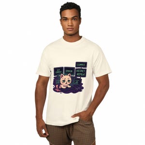 A man wearing a white t-shirt with a graphic design depicting a cat with a computer monitor and text that says "COMMIT", "REPLACE", and "REPEAT".