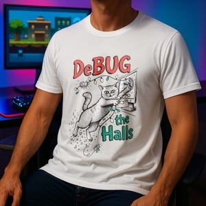 Könnte beinhalten: Weißes T-Shirt mit einer Katzenillustration und dem Text "DeBUG the Halls". Die Katze interagiert mit einem Computermonitor, der mit Lichterketten geschmückt ist. Das Design ist eine humorvolle Interpretation des Computer-Debugging.