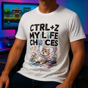 Puede incluir: Camiseta blanca con el texto "CTRL+Z MY LIFE CHOICES" en negro, verde y morado. Un gato de dibujos animados está enredado en cables con un portátil y otros aparatos electrónicos. Signos de interrogación a ambos lados del gato.