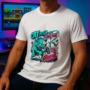 Puede incluir: Camiseta blanca con un diseño de gato turquesa golpeando un botón "ENTER" rosa con un martillo. El texto "CAT mit-m oops" está encima del gato en turquesa y rosa. La camiseta es de cuello redondo.