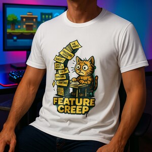May include: White t-shirt with a cartoon cat looking concerned, sat at a desk with gaming-related labels. The text "FEATURE CREEP" is printed in yellow and black. The background shows a computer screen.