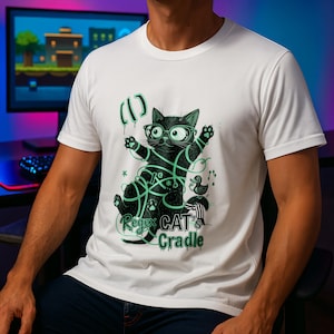 May include: White t-shirt with a graphic of a black cat wearing glasses and green string. The text "Regex CAT's Cradle" is below the cat. A small duck and musical notes are also in the design.