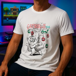 Puede incluir: Camiseta blanca con un gato de dibujos animados sosteniendo una tecla "CTRL-Z". El gato tiene ojos grandes y está debajo de un árbol decorado con adornos. El texto "CATROL-Z" está encima del árbol en una fuente juguetona.