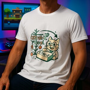 Puede incluir: Camiseta blanca con un gato de dibujos animados con gafas y sosteniendo una tecla "CTRL-Z". El diseño incluye un árbol de Navidad con adornos y el texto "CATrol-Z Noel". Prenda de vestir informal.