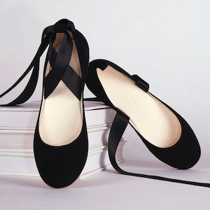 pair of black nubuck ballerinas with long satin straps shown from the front