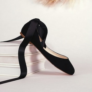 side view of a black suede ballerina with satin ribbons