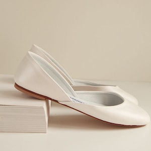 side view of a pair of shimmery smooth pearl ivory leather wedding ballet flats