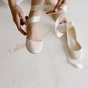 Close up of a bride tying ribbons of her wedding shoes around the ankles