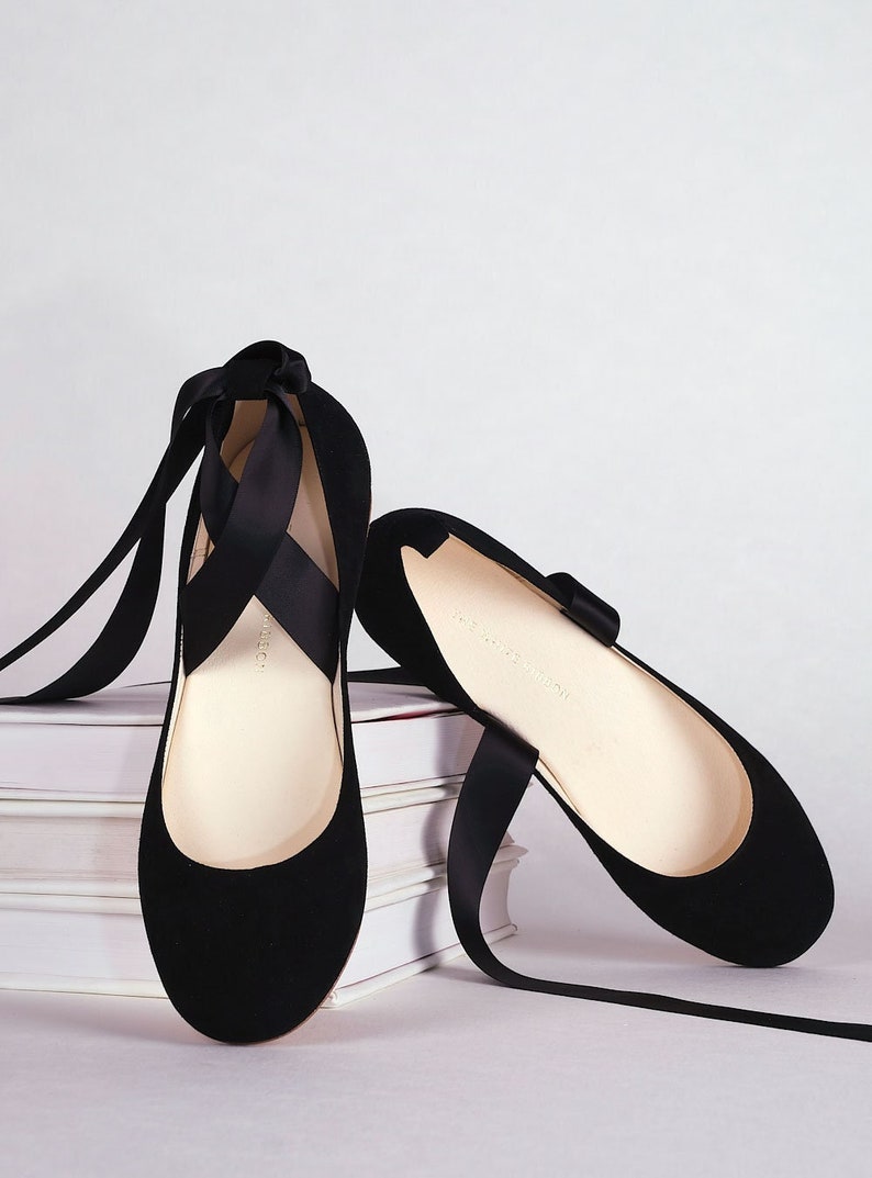 pair of black nubuck ballerinas with long satin straps shown from the front