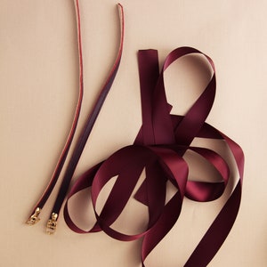 detailed photo of a pair of burgundy leather ankle straps and matching satin ribbons