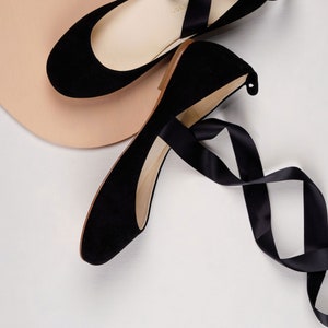 top and side view of a pair of black nubuck ballerinas with long satin straps