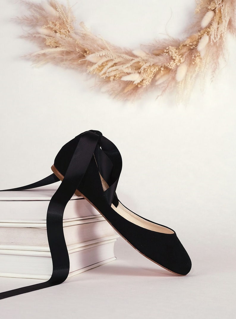 side view of a black suede ballerina with satin ribbons