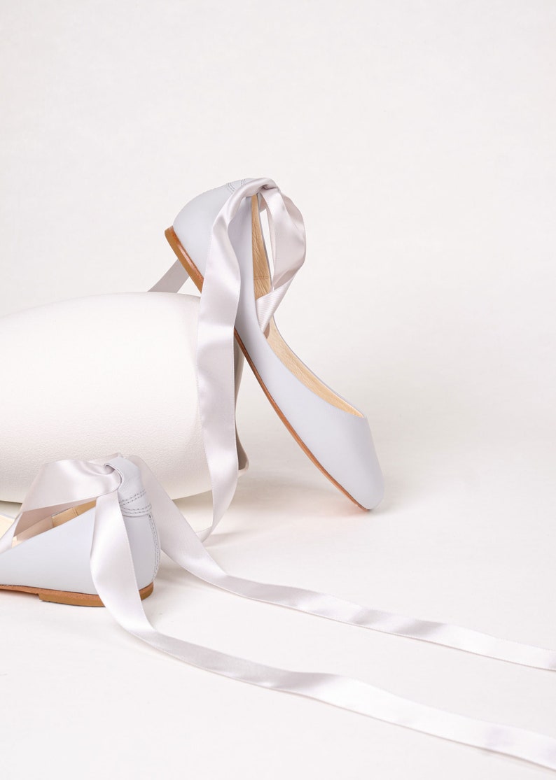 picture of the back and side of a pair of light grey smooth leather ballet flats with long satin straps