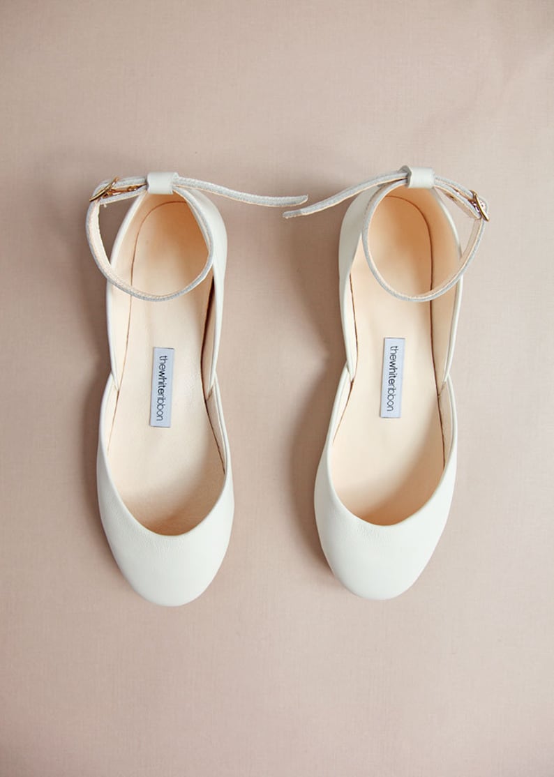 Top view of flat shoes with ankle straps on peach tone background