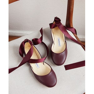 top/front view of a pair of bordeaux ballet flats with matching satin ribbons attached