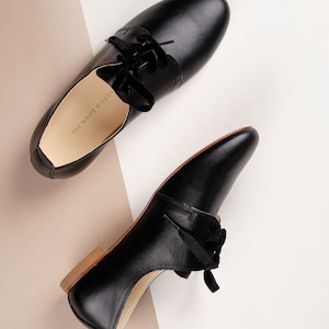 side and top view of a pair of smooth black leather derby shoes with thick laces