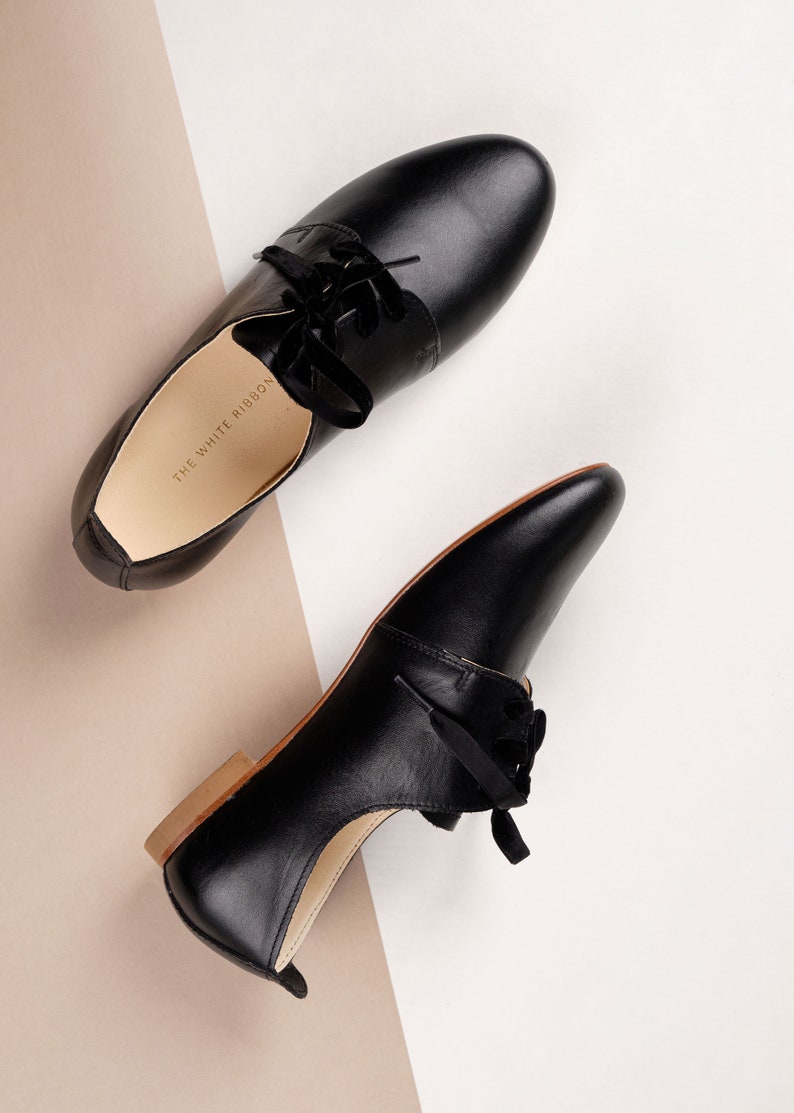 side and top view of a pair of smooth black leather derby shoes with thick laces