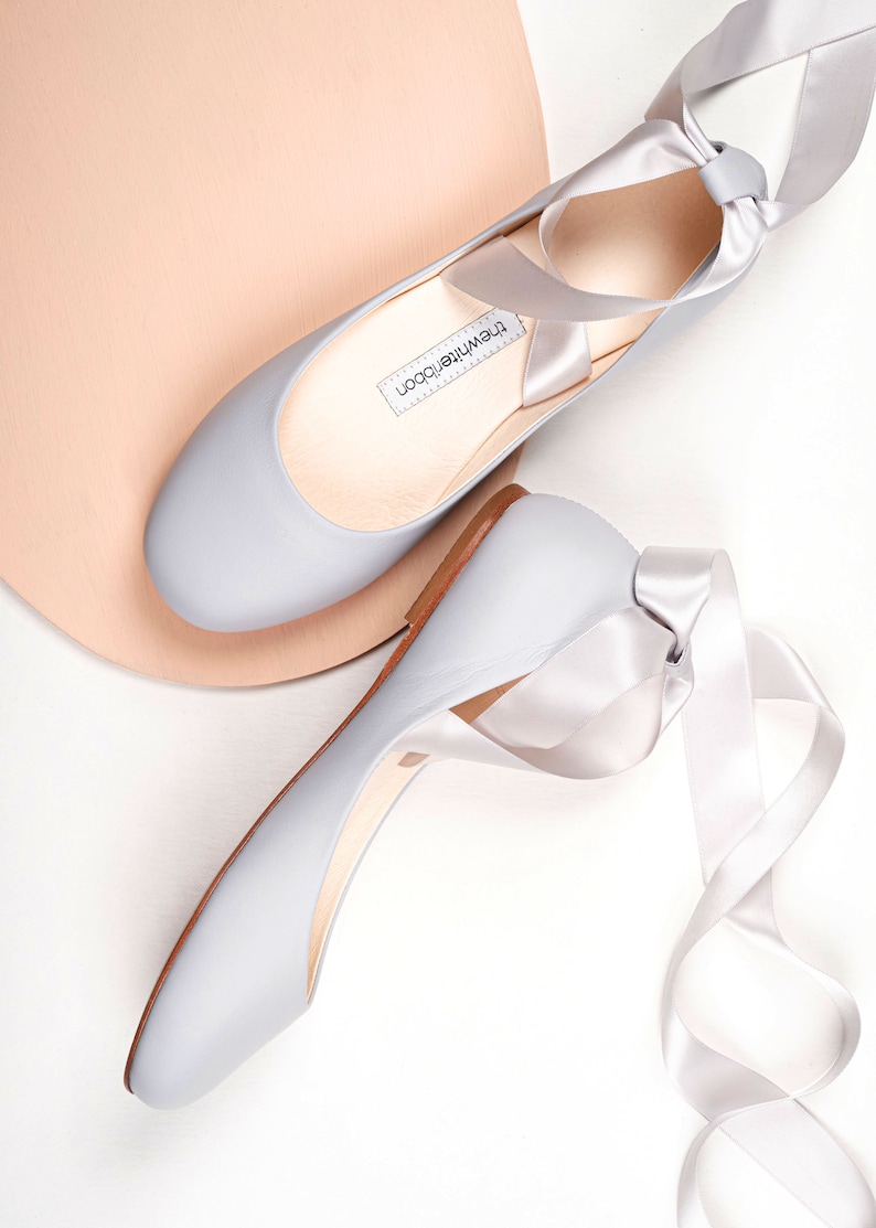 top and side show of a pair of light grey smooth leather ballet flats with long satin straps