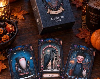 May include: A deck of Expelliarmus Tarot cards in a dark gray box featuring a crest with a blue and pink feather. Three cards are displayed face up, titled The Hermit, Death, and The Fool, each showcasing detailed fantasy illustrations in ornate frames.