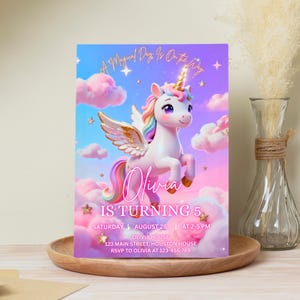 K&ouml;nnte beinhalten: Eine Geburtstagseinladung mit einem Einhorn mit goldenem Horn, Fl&uuml;geln und einer Regenbogenm&auml;hne und -schwanz. Auf der Einladung steht "Olivia wird 5" mit Veranstaltungsdetails. Der Hintergrund ist ein Farbverlauf aus Blau, Rosa und Lila mit Wolken und Sternen.