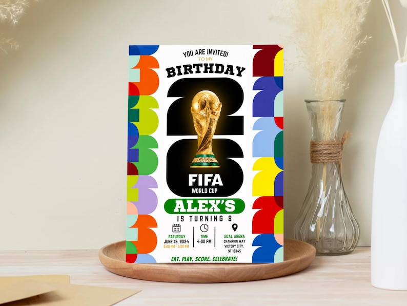 May include: A rectangular birthday invitation card featuring a large gold FIFA World Cup trophy graphic, the text "YOU ARE INVITED! TO MY BIRTHDAY", "ALEX'S IS TURNING 8", and "EAT, PLAY, SCORE, CELEBRATE!" with colorful geometric borders on the sides.