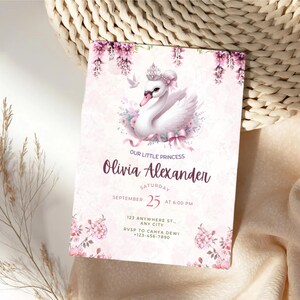 K&ouml;nnte beinhalten: Eine rosa Einladungskarte mit einer Schwan-Illustration, floralen Akzenten und dem Text "Our Little Princess Olivia Alexander." Die Karte enth&auml;lt Eventdetails: Samstag, 25. September um 18:00 Uhr und einen RSVP-Kontakt.