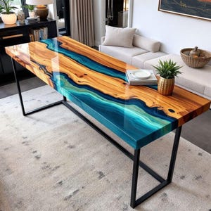 May include: A rectangular wooden table with a glossy finish. The table features a striking design with a river of blue and turquoise resin flowing through the centre of the natural wood grain. The table is supported by black metal legs.