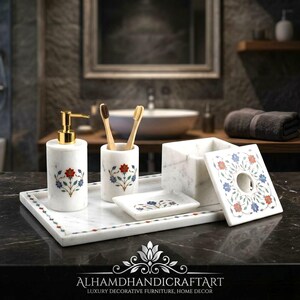 Può includere: Un set di accessori da bagno in marmo bianco composto da un dispenser di sapone con pompa dorata, un portaspazzolino, un portasapone e un porta fazzoletti, decorati con motivi floreali intarsiati in pietre rosse, blu e verdi.