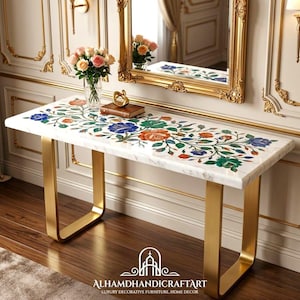 May include: A rectangular console table featuring a white marble top inlaid with a colorful floral pattern of blue, orange, and green stone. The table is supported by two U-shaped gold metal legs. A glass vase with flowers sits on the surface.