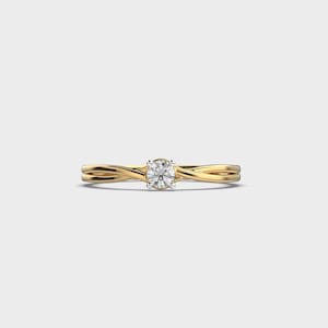 May include: A gold engagement ring with a round, clear diamond center stone. The band features a twisted design. The ring is set against a plain white background.